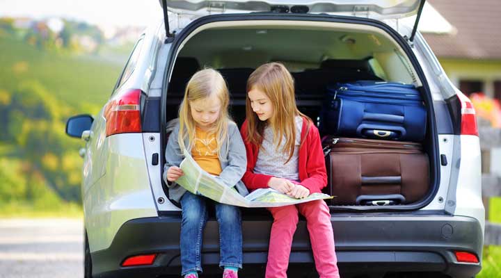 children sitting on the car boot looking at a map