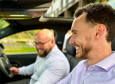 Two people in the front seats of a car smiling