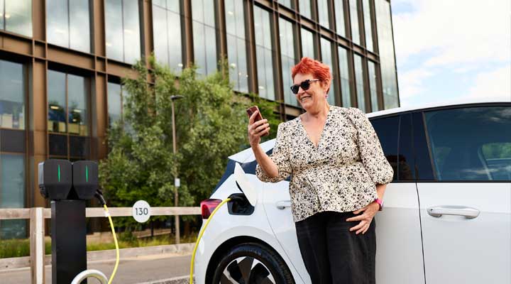 Lady checking her phone while her car is charging.