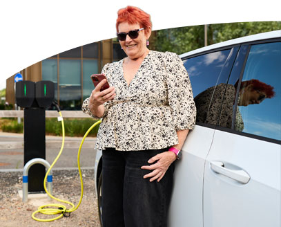 Lady standing outside her car using her phone to charge her vehicle