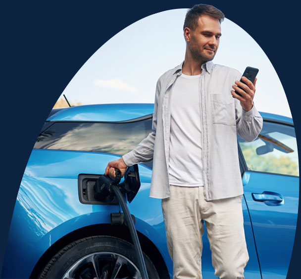man charging his car while using his phone