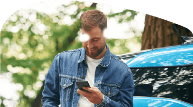 Person looking at phone whilst leaning against car